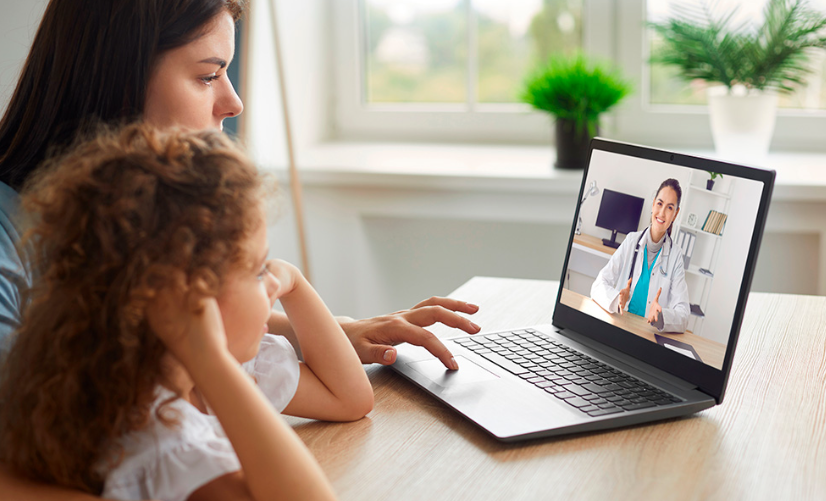 Madre con su hija realizando una consulta de salud online en casa